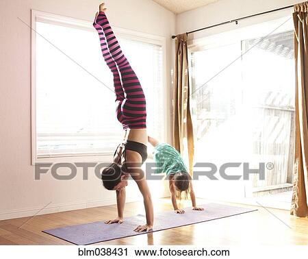 Stock Image - Mother and daughter practicing yoga in studio. Fotosearch