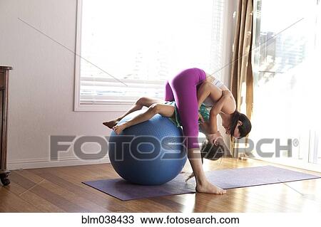 Stock Image - Mother and daughter practicing yoga in studio. Fotosearch