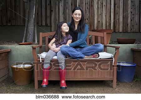 Mother and daughter sitting on bench in backyard View Large Photo Image Stock Photo - Mother and daughter sitting on bench in backyard. Fotosearch
