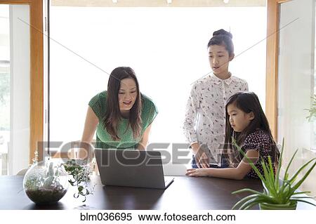 Mother and daughters using laptop in dining room View Large Photo Image Stock Photography - Mother and daughters using laptop in dining room. Fotosearch