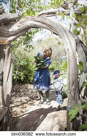 Stock Image - Mother and son carrying plants in backyard. Fotosearch