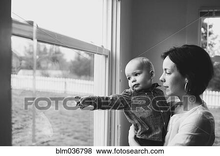 Mother and son looking out window View Large Photo Image Stock Photo - Mother and son looking out window. Fotosearch