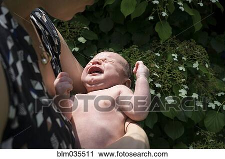 Stock Image - Mother holding crying baby in arms. Fotosearch