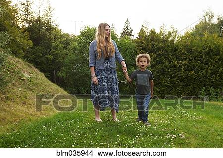 Picture - Mother holding hand of son in rural field. Fotosearch