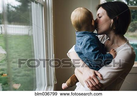 Stock Photo - Mother kissing son at window. Fotosearch