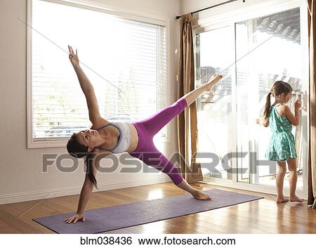 Stock Photograph - Mother practicing yoga in studio near daughter. Fotosearch