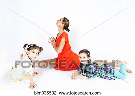 Mother practicing yoga with playful daughters View Large Photo Image Stock Image - Mother practicing yoga with playful daughters. Fotosearch