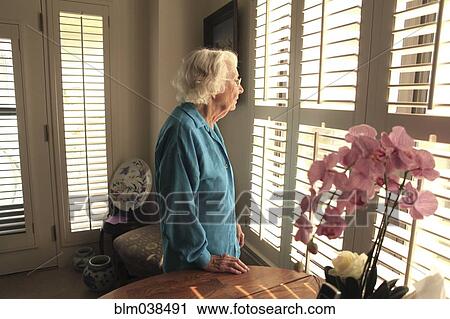 Stock Image - Older Caucasian woman looking out window. Fotosearch