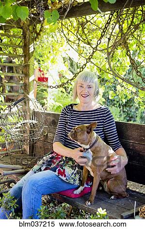 Stock Photography - Older Caucasian woman petting dog in garden. Fotosearch