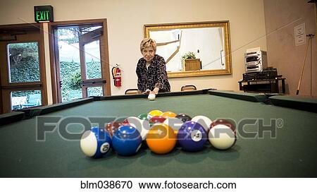 Stock Image - Older Caucasian woman playing pool. Fotosearch