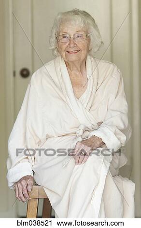 Stock Image - Older Caucasian woman sitting in bathrobe. Fotosearch
