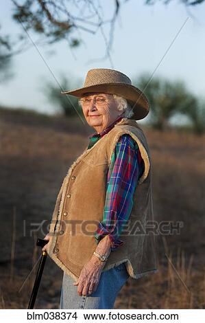 Picture - Older Caucasian woman walking with cane in field. Fotosearch