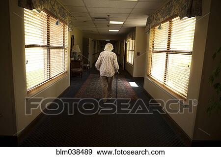 Stock Photo - Older Caucasian woman walking with cane in retirement home. Fotosearch