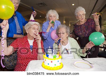 Stock Photography - Older friends celebrating birthday in retirement home. Fotosearch