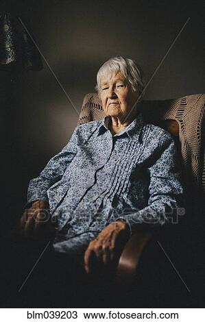 Stock Image - Older mixed race woman sitting in armchair. Fotosearch