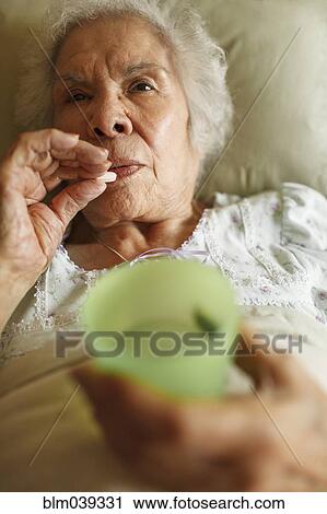 Older mixed race woman taking medication in bed View Large Photo Image Stock Image - Older mixed race woman taking medication in bed. Fotosearch