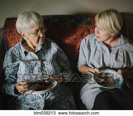 Older woman and granddaughter eating on sofa View Large Photo Image Stock Image - Older woman and granddaughter eating on sofa. Fotosearch