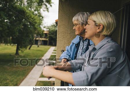 Stock Image - Older woman and granddaughter standing on balcony. Fotosearch