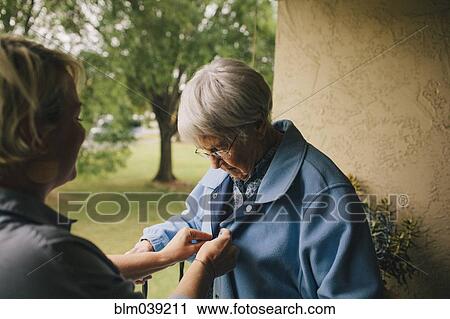 Stock Image - Older woman and granddaughter standing on balcony. Fotosearch