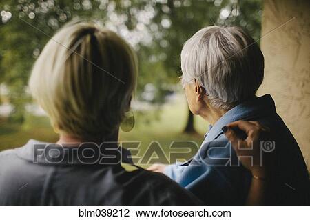 Stock Image - Older woman and granddaughter standing on balcony. Fotosearch