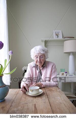 Stock Photo - Older woman drinking tea at table. Fotosearch
