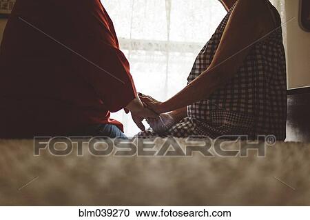 Older woman holding hand of daughter on bed View Large Photo Image Stock Image - Older woman holding hand of daughter on bed. Fotosearch