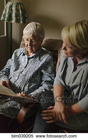Stock Photography - Older woman reading to granddaughter in living room. Fotosearch