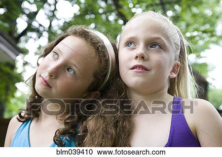 Stock Image - Pensive Caucasian girls standing outdoors. Fotosearch
