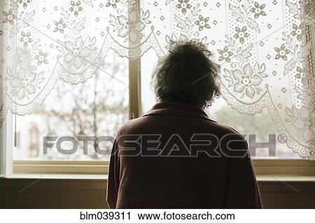 Stock Image - Pensive mixed race older woman looking out window. Fotosearch
