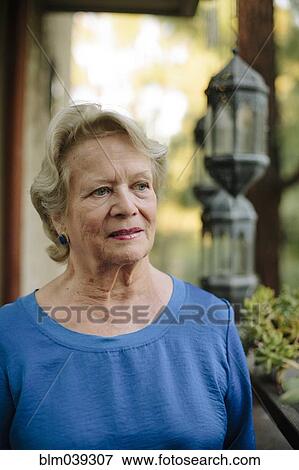 Stock Photo - Pensive older woman standing on porch. Fotosearch