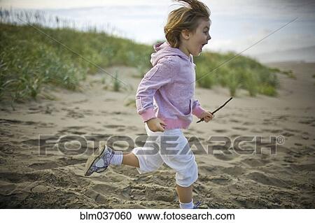Stock Image - Playful girl running on beach. Fotosearch