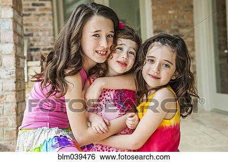 Stock Photograph - Playful sisters hugging outdoors. Fotosearch
