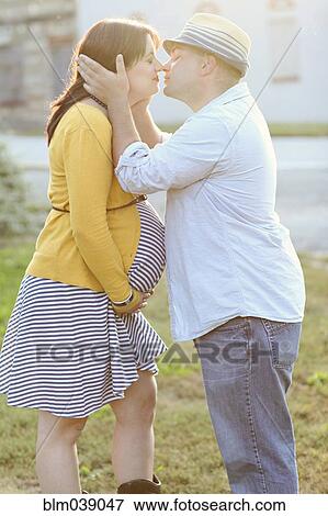 Pregnant couple kissing in sunny field View Large Photo Image Stock Photo - Pregnant couple kissing in sunny field. Fotosearch