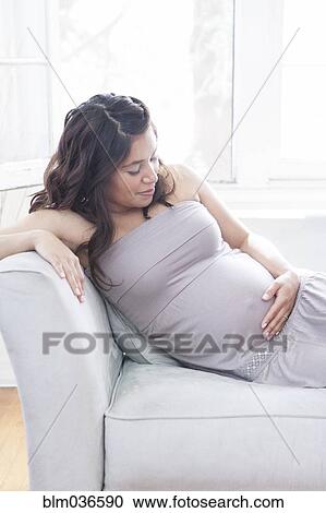 Pregnant Hispanic woman holding belly on sofa View Large Photo Image Stock Image - Pregnant Hispanic woman holding belly on sofa. Fotosearch