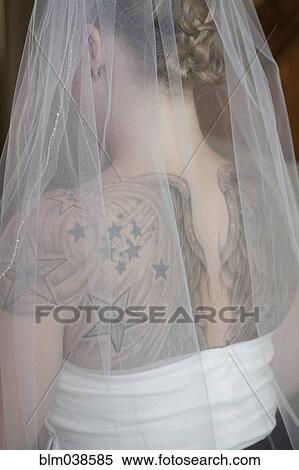 Stock Photography - Rear view of Caucasian bride in veil with tattoos on back. Fotosearch