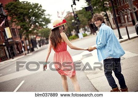 Rear view of couple walking on city sidewalk View Large Photo Image Stock Photo - Rear view of couple walking on city sidewalk. Fotosearch