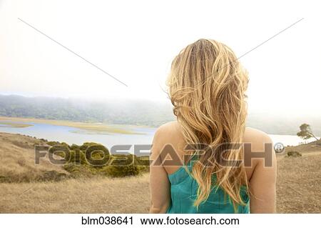 Stock Image - Rear view of woman admiring rural landscape from hilltop. Fotosearch