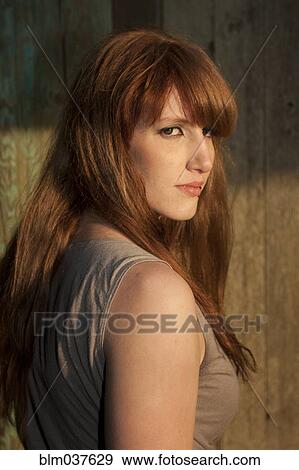 Rear view of woman standing by wooden fence View Large Photo Image Stock Photo - Rear view of woman standing by wooden fence. Fotosearch