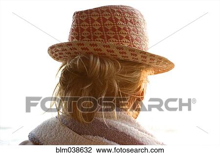 Stock Image - Rear view of woman wearing straw hat. Fotosearch