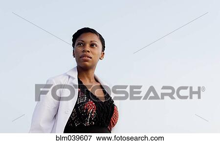 Stock Photo - Serious doctor standing under blue sky. Fotosearch