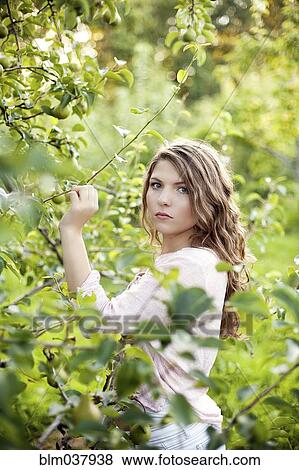 Stock Photo - Serious woman examining plants in rural field. Fotosearch