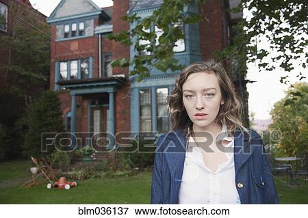 Stock Photo - Serious woman standing in front yard. Fotosearch