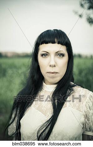 Stock Photography - Serious woman standing in rural field. Fotosearch