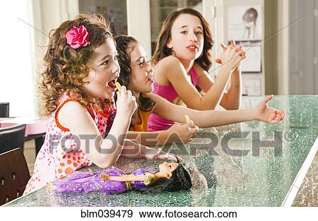 Stock Photo - Sisters sitting at counter. Fotosearch