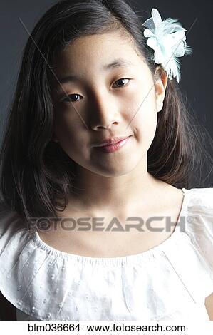 Smiling Asian girl wearing flower in her hair View Large Photo Image Picture - Smiling Asian girl wearing flower in her hair. Fotosearch