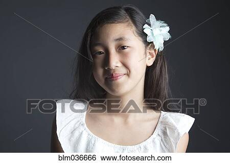 Stock Photograph - Smiling Asian girl wearing flower in her hair. Fotosearch