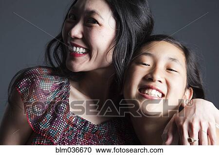 Stock Image - Smiling Asian mother and daughter hugging. Fotosearch