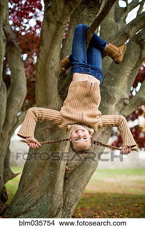 Smiling girl hanging upside-down in tree View Large Photo Image Picture - Smiling girl hanging upside-down in tree. Fotosearch