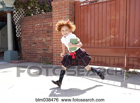 Stock Photograph - Smiling girl in school uniform running in driveway. Fotosearch