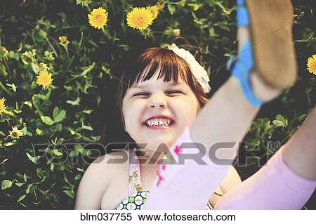 Stock Photography - Smiling girl playing in grass with flowers, . Fotosearch